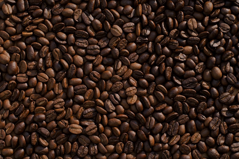 A small digital scale on a kitchen counter with coffee beans, a dripper, and a mug nearby.