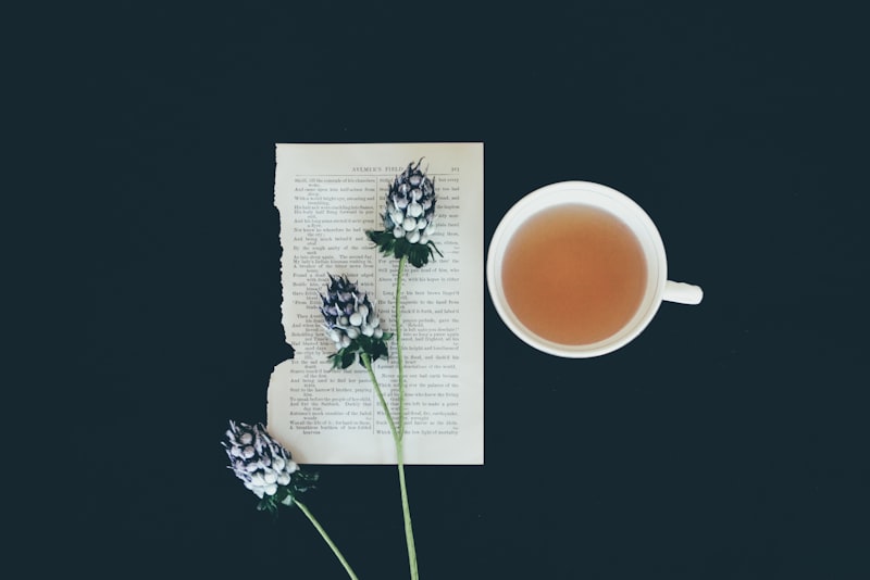 A glass cup of herbal infusion with fresh herbs resting nearby