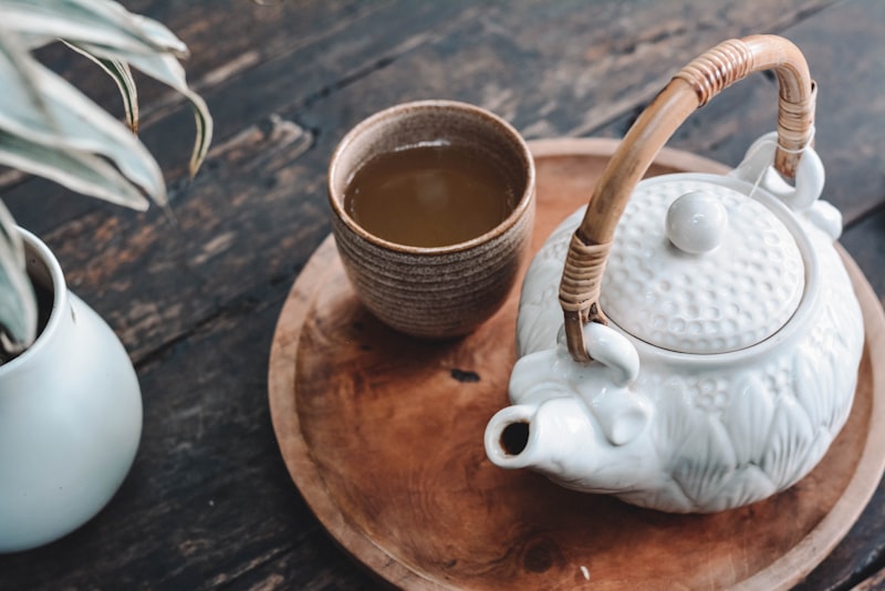 A cup of freshly brewed green tea beside loose green tea leaves