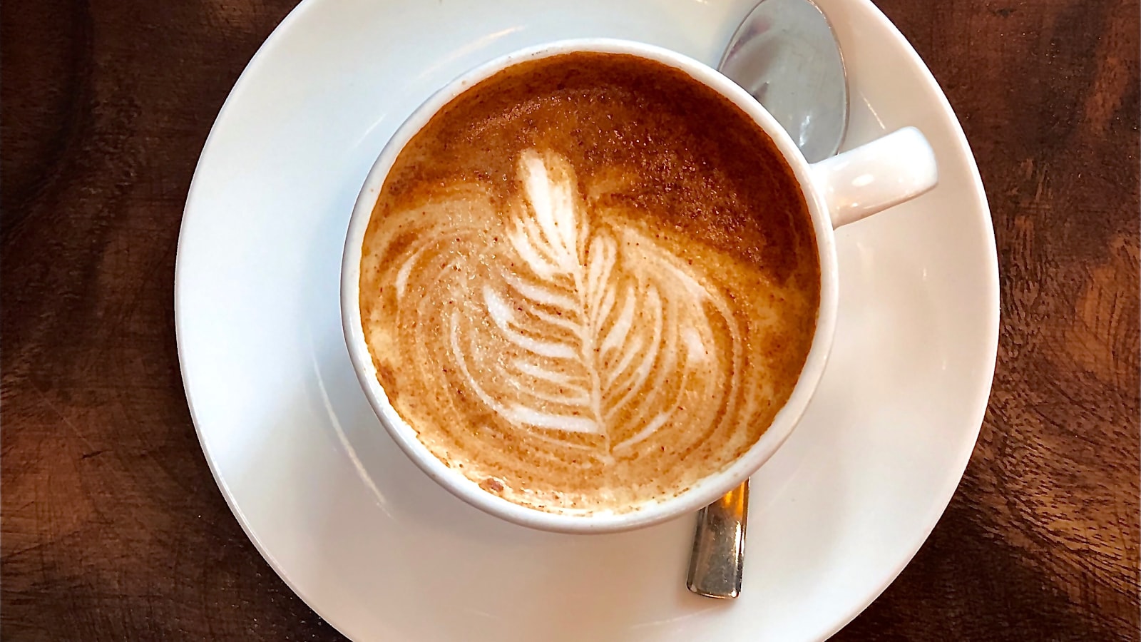 Steamed milk being poured into a cup of espresso to make latte art.