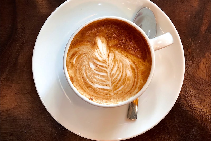Steamed milk being poured into a cup of espresso to make latte art.