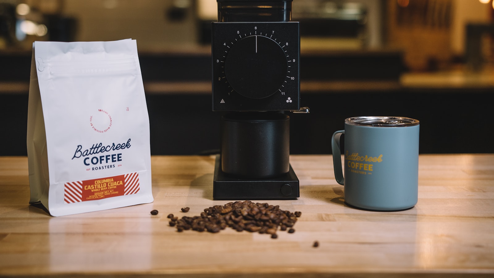An airtight coffee storage canister on a counter with a scoop and whole beans beside it.